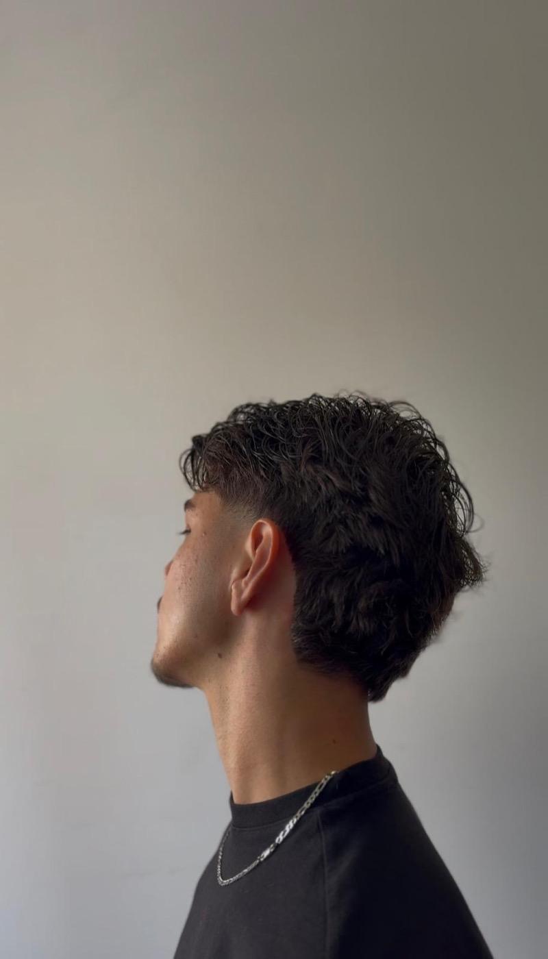 Corte em cabelo ondulado com degradê médio
